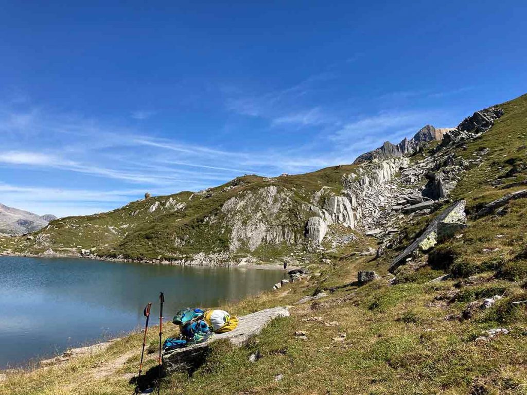 Bergsee mit Wanderstöcken und Wanderruckssack