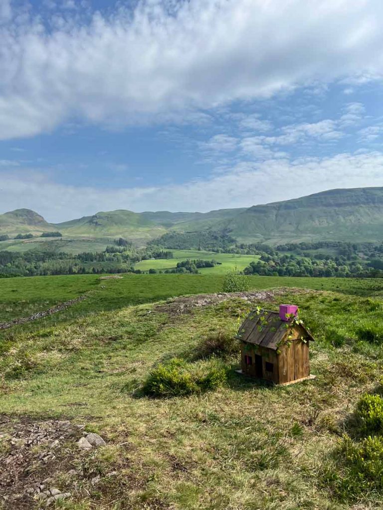 Landschaft mit einem Miniaturhaus davor